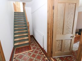 A hallway with patterned tile floor a wooden staircase and an open wooden door at Llanwern Farm in Fishguard