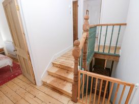 A wooden staircase with green balusters and a safety gate next to a bedroom door at Llanwern Farm in Fishguard