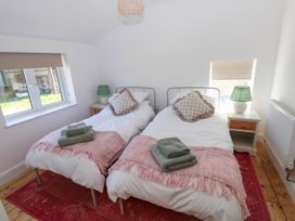 A bedroom with two single beds each with pink throws and green towels at Llanwern Farm in Fishguard