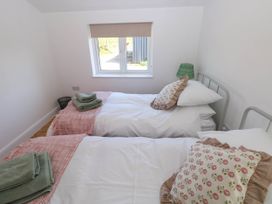 A bedroom with two single beds with floral cushions and folded towels at Llanwern Farm in Fishguard