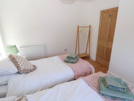 A bedroom with two single beds green towels wooden door and wooden clothes rack at Llanwern Farm in Fishguard