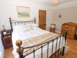 A bedroom with a metal bed frame a wooden dresser a wooden chair and a nightstand at Llanwern Farm Fishguard