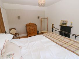 A bedroom with a wooden chest of drawers chair and a bed at Llanwern Farm in Fishguard