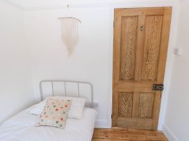 A bedroom with a bed with heart patterned pillows a macrame wall hanging and a wooden door at Llanwern Farm in Fishguard