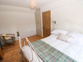 A bedroom with a metal bed a patterned blanket a wooden chair a wooden door and cupboards at Llanwern Farm in Fishguard