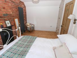 A bedroom with a white metal bed frame a wooden floor a chair a wooden door and a brick wall with a radiator at Llanwern Farm in Fishguard
