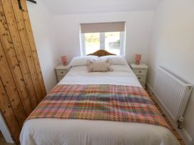 A bedroom with a bed with a patterned blanket and two bedside tables with lamps at Llanwern Farm in Fishguard