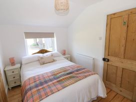 A bedroom with a bed flanked by two nightstands and a wooden door at Llanwern Farm in Fishguard