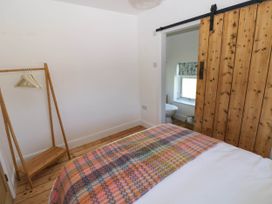 A bedroom with a wooden clothes rack and a bed with a colorful blanket at Llanwern Farm in Fishguard