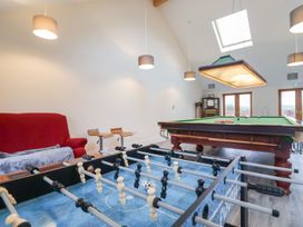 A game room with a foosball table a pool table a red sofa and wooden stools at Mill Cottage in Aylesbeare