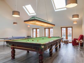 A game room with a snooker table ping pong table red armchair and stools at Mill Cottage in Aylesbeare