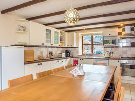 A kitchen with wooden dining table and chairs white cabinets and a refrigerator at Mill Cottage in Aylesbeare