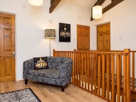 An upper hallway with wooden doors a patterned loveseat and wooden railing at Mill Cottage in Aylesbeare