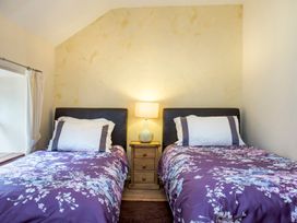 A bedroom with two single beds with floral bedspreads and a nightstand with a lamp between them at Mill Cottage in Aylesbeare