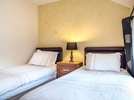A bedroom with two single beds separated by a nightstand with a lamp at Mill Cottage in Aylesbeare