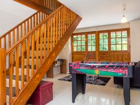 A room with wooden stairs a foosball table a small shelf with books and a sofa near wooden window doors at Mill Cottage in Aylesbeare