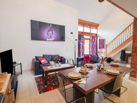 A living room with two sofas a coffee table dining table set with plates and glasses and a staircase at Cob Barn in Aylesbeare