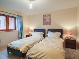 A bedroom with two single beds bedside tables and lamps at Cob Barn in Aylesbeare