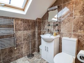 A bathroom with a white sink and cabinet a toilet a small mirror and a skylight window at Cob Barn in Aylesbeare