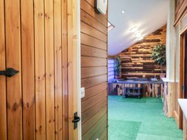 An interior view of a room with wooden paneled walls green carpet and a hot tub at Cob Barn in Aylesbeare