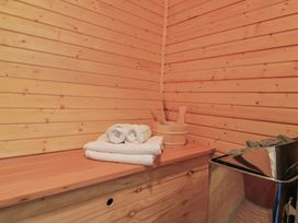 An interior of a wooden sauna with towels and a bucket with ladles on a bench and a sauna heater with stones