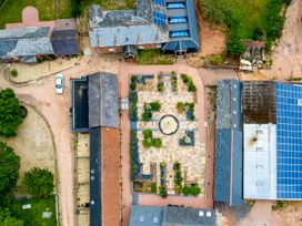 An aerial view of a property with multiple buildings arranged around a central courtyard with a fountain and garden at Cob Barn in Aylesbeare