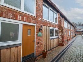 A row of brick cottages with wooden lower walls and several windows along a paved pathway at Ivy Cottage in Aylesbeare