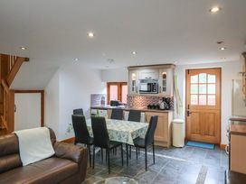A kitchen with dining table and chairs near a wooden door at Ivy Cottage in Aylesbeare
