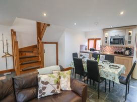 A kitchen and dining area with a wooden staircase and a brown leather sofa at Ivy Cottage in Aylesbeare
