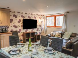 A dining area with set table and a living room with a sofa and wall-mounted TV at Ivy Cottage in Aylesbeare
