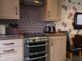 A kitchen with wooden cabinets a double oven a toaster and a tiled backsplash at Ivy Cottage in Aylesbeare