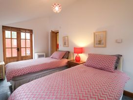 A bedroom with two single beds pink chevron bedding a red lamp and wooden doors at Ivy Cottage in Aylesbeare