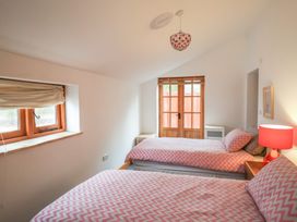A bedroom with two single beds with pink patterned bedding and a window with wooden blinds at Ivy Cottage in Aylesbeare
