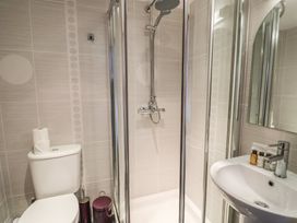 A bathroom with a toilet a shower enclosed by glass doors and a sink with toiletries at Ivy Cottage in Aylesbeare