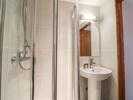 A bathroom with a shower enclosure a white pedestal sink a mirror and toiletries at Ivy Cottage in Aylesbeare