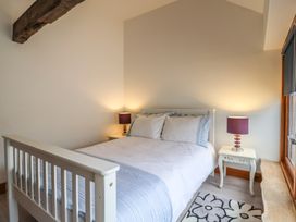 A bedroom with a white bed, two bedside tables with lamps, a window, and a rug at Ivy Cottage in Aylesbeare