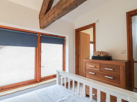 A bedroom with wooden chest of drawers blue window blinds and a white bed frame at Ivy Cottage in Aylesbeare