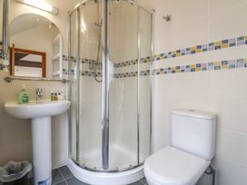 A bathroom with a corner shower enclosure a pedestal sink with soap and toiletries and a toilet at Ivy Cottage in Aylesbeare
