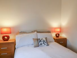 A bedroom with a double bed between two wooden bedside tables with red lamps at Ivy Cottage in Aylesbeare