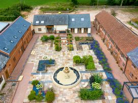 Aerial view of a courtyard with a central fountain surrounded by paved walkways and three buildings at Ivy Cottage in Aylesbeare