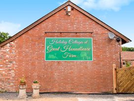 A brick wall with a green sign for holiday cottages and two flower pots at Great Houndbeare Farm