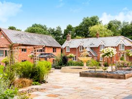 A courtyard with a stone fountain surrounded by flower beds and two brick houses in Aylesbeare