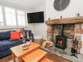 A snug room with a fireplace and seating area at Daisy Cottage in Wigton