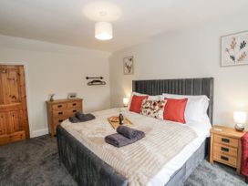 A bedroom with a large bed and wooden furniture at Daisy Cottage in Wigton