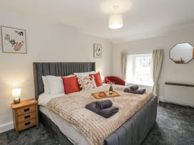 A bedroom with a large bed and decorative items at Daisy Cottage in Wigton