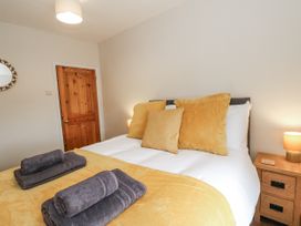 A bedroom with a bed and nightstand at Daisy Cottage in Wigton
