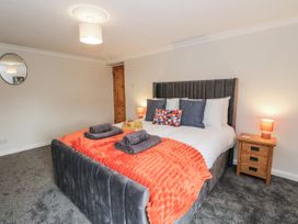 A bedroom with a bed and bedside table at Daisy Cottage in Wigton