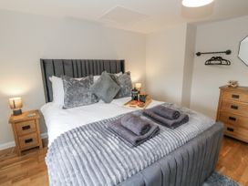A bedroom with a bed, nightstand, and dresser at Daisy Cottage in Wigton