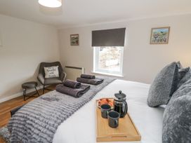 A bedroom with a bed and armchair at Daisy Cottage in Wigton