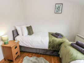 A bedroom with two beds and a nightstand at Daisy Cottage in Wigton
